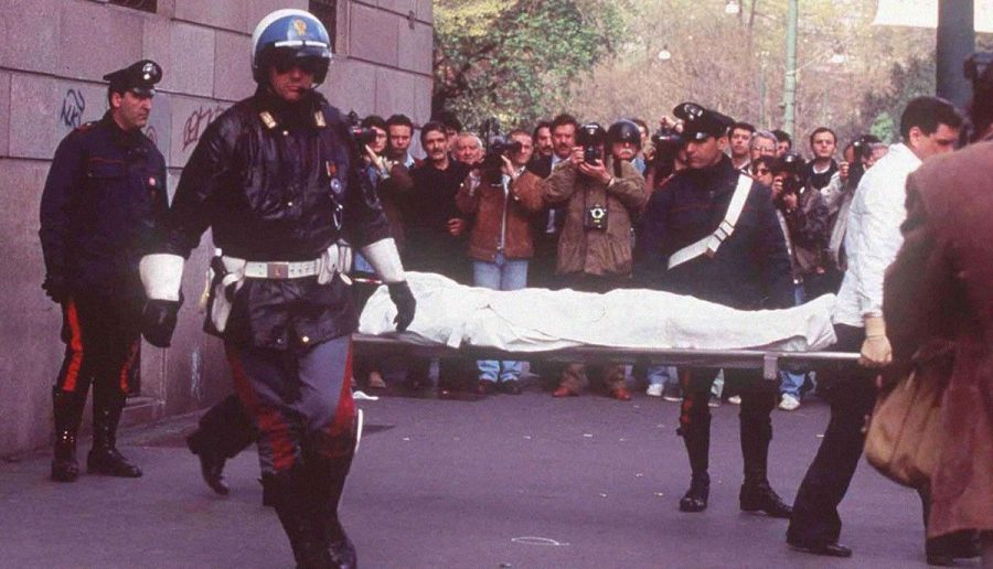 Maurizio Gucci’s corpse was covered in order to cover fatalities from the public. Local officers are shown escorting his body in order to take it to the morgue. 
