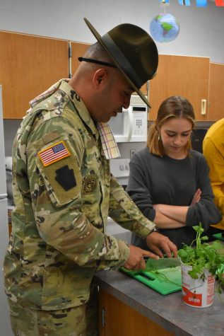With a smile, Sergeant Molina teaches junior Hayden Thomas how to correctly cut parsley, one of the many teaching moments at the MRE Chopped Competition.