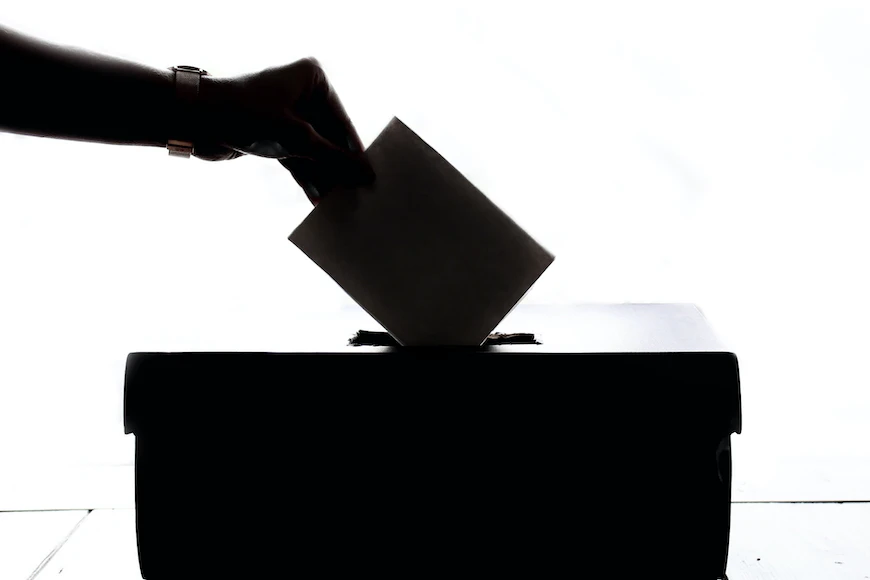 Casting a vote in a ballot box.