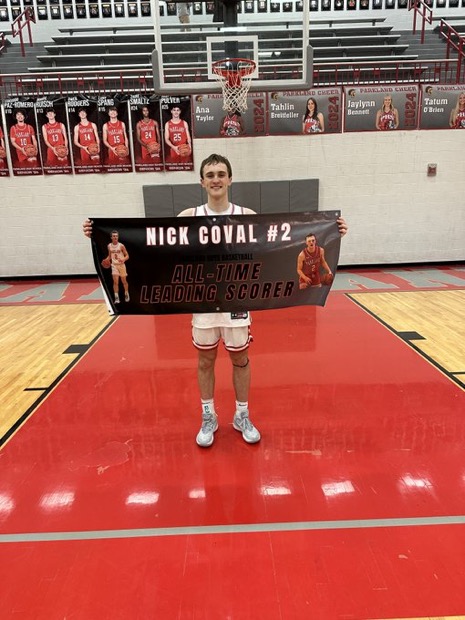 Nick Coval posing with a sign on the court after he broke the all-time scoring record. 