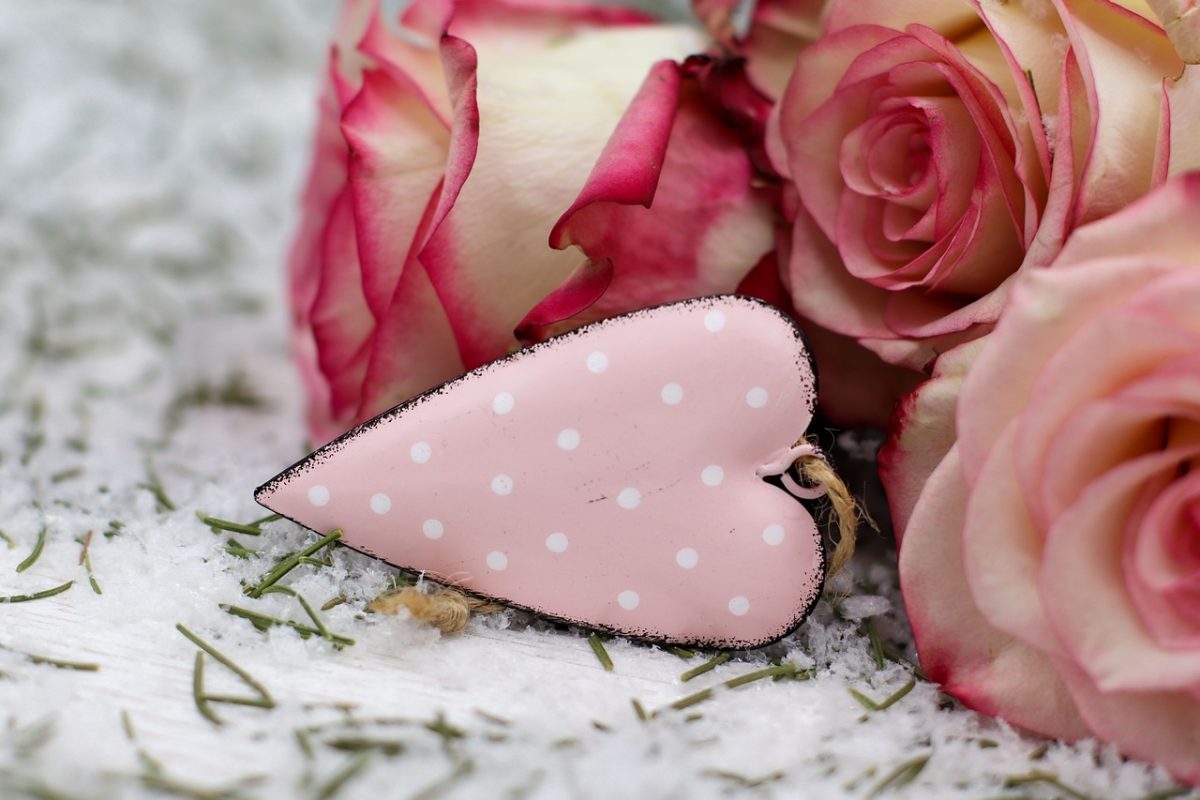 White and pink roses laying on a black and white floral background with a pink and white polka dot heart.