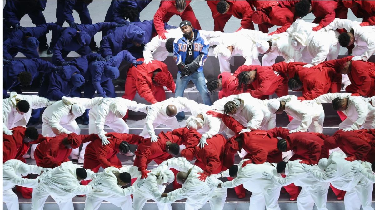 Kendrick Lamar in the midst of his Super Bowl half-time performance, surrounded by back up dancers dressed in patriotic colors to form an American flag in the background.